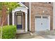 Welcoming brick townhouse entry featuring classic architectural details, a garage, and manicured bushes at 1880 Garbrooke Cv, Lawrenceville, GA 30046