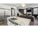 A view of the kitchen island with stainless sink, adjacent to a large stainless refrigerator and open-concept living space at 2020 Bixby Se St, Atlanta, GA 30317