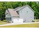 Home exterior displays light gray siding, a two-car garage, and lush green yard at 445 Boulder Crest Trl, Villa Rica, GA 30180