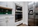 Close-up of stainless steel appliances with white cabinets and green subway tile backsplash at 445 Boulder Crest Trl, Villa Rica, GA 30180