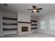 Open living room with a brick fireplace, wood mantle, built-in shelving, ceiling fan, and carpet flooring at 445 Boulder Crest Trl, Villa Rica, GA 30180