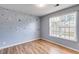 Bright bedroom with wood-look floors, large window with blinds, and stylish decorative polka dots on accent wall at 447 Wallace Way, Rockmart, GA 30153