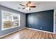 Bedroom with wood look flooring, ceiling fan, large window offering natural light and accent wall at 447 Wallace Way, Rockmart, GA 30153