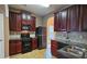 Stylish kitchen featuring dark wood cabinetry, black appliances, and arched openings to adjacent rooms at 3479 Lake Forge Dr, Fairburn, GA 30213