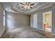 Primary bedroom featuring carpeted floors, gray walls, trey ceiling, ceiling fan, and entrance to the en suite bathroom at 604 Lexington Way, Woodstock, GA 30189