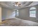 Spacious main bedroom showcasing a trey ceiling with ceiling fan, carpeted floors, and an abundance of natural light at 604 Lexington Way, Woodstock, GA 30189