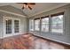 Bright sunroom featuring hardwood floors, wood-paneled walls, ceiling fan, and three large windows overlooking the backyard at 604 Lexington Way, Woodstock, GA 30189