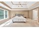 Bright main bedroom with a tray ceiling, fan, carpeted floors and large windows with view at 902 Preserve Bluff Dr, Buford, GA 30518
