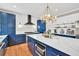 Bright kitchen with blue cabinets, white countertops, an island, modern lighting, and wood floors at 902 Preserve Bluff Dr, Buford, GA 30518