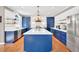 Spacious modern kitchen featuring blue cabinets, a center island, stainless appliances, and wood floors at 902 Preserve Bluff Dr, Buford, GA 30518