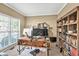 Bright home office with a large window, wooden desk, and a wall of built-in bookshelves at 902 Preserve Bluff Dr, Buford, GA 30518