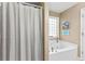 Bathroom with a white tub, gray shower curtain, and a window with plants at 100 Lantana Dr, Locust Grove, GA 30248