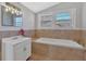 Bathroom featuring a large soaking tub, vanity, neutral tiling, and natural light at 345 Wellington Sw St, Atlanta, GA 30310