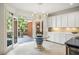 Bright kitchen with white cabinets, stone floors, and glass table next to open doors to an outdoor patio at 1285 Wesley Nw Pl, Atlanta, GA 30327