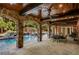 A covered outdoor patio with stone columns, ceiling fans, and dining table overlooking a tranquil pool and waterfall at 1285 Wesley Nw Pl, Atlanta, GA 30327