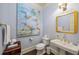 Stylish powder room featuring grey walls, hardwood floors, and a gold-framed mirror above a pedestal sink at 1285 Wesley Nw Pl, Atlanta, GA 30327