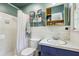 Bright bathroom with a white tiled shower, blue vanity, and convenient built-in storage shelves at 4730 Geneva Sw Dr, Lilburn, GA 30047