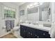 Clean bathroom with white tile, a blue vanity, and a window offering natural light at 4730 Geneva Sw Dr, Lilburn, GA 30047