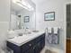 Well-lit bathroom featuring a blue vanity with a white countertop, large mirror, and ample storage space at 4730 Geneva Sw Dr, Lilburn, GA 30047