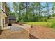 Spacious backyard with a stone patio, gravel landscaping, and lush green trees at 4840 Moon Rd, Powder Springs, GA 30127