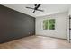 Large bedroom featuring a ceiling fan, wood floors, a dark accent wall, and a bright window at 4840 Moon Rd, Powder Springs, GA 30127
