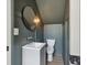 This half bathroom has a vessel sink, dark green walls, a round mirror, and a toilet at 4840 Moon Rd, Powder Springs, GA 30127