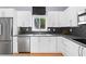 Well-lit kitchen boasts stainless steel appliances, black backsplash, and sleek white cabinets at 5148 Stratham Dr, Dunwoody, GA 30338