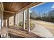 Covered porch with stone wall, white pillars, wood ceiling and decking, and verdant landscaping at 121 Harmony Oaks Trl, Canton, GA 30115
