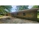 Exterior view of the brick home, showcasing a small patio area and a glimpse of the backyard and wooded surroundings at 2886 The Fontainebleau Sw, Atlanta, GA 30331