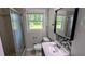 Bathroom with a shower, toilet, sink, decorative mirror, and a window with natural lighting at 1091 Luther Sw Dr, Mableton, GA 30126