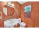 Cozy bathroom with wood paneling, a round mirror, and natural light from the window at 4440 Coventry Ne Ct, Roswell, GA 30075