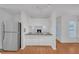 Efficient kitchen boasts white cabinets, stainless fridge, stone countertop, and a fireplace view at 4440 Coventry Ne Ct, Roswell, GA 30075