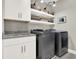 Functional laundry room with white cabinetry, stainless steel appliances, and shelving at 1626 Aldworth Se Pl, Atlanta, GA 30339