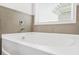 Close-up view of a soaking tub with chrome faucet, tiled walls, and a window at 3219 Colchester St, Douglasville, GA 30135