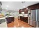 Spacious kitchen boasts stainless appliances, dark wood cabinetry, tile backsplash, and adjacent dining area at 3415 Trickum Rd, Woodstock, GA 30188