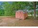 A rustic outbuilding sits nestled among mature trees on the property grounds at 3415 Trickum Rd, Woodstock, GA 30188