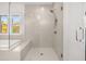 Well-lit bathroom showcasing a glass-enclosed shower with white subway tile and a soaking tub beneath a window at 739 Marlay Sw Ln, Powder Springs, GA 30127