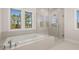 Bright bathroom features a soaking tub under large windows and a glass enclosed shower at 739 Marlay Sw Ln, Powder Springs, GA 30127