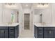Well-lit bathroom with dual vanities, modern fixtures, large mirrors, and neutral tile flooring at 739 Marlay Sw Ln, Powder Springs, GA 30127