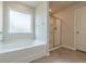 Bright bathroom with tub next to window and enclosed glass door shower at 3868 Sweet Iris Cir, Loganville, GA 30052