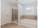 Bathroom features a glass enclosed shower and a soaking tub near a window at 674 Chadmon Court Trce, Dacula, GA 30019