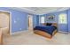 Spacious bedroom with blue walls, large windows, plush carpeting, and a tray ceiling with a ceiling fan at 674 Chadmon Court Trce, Dacula, GA 30019