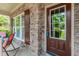 Close-up of front porch with brick trim, rocking chairs, and a welcoming front door at 674 Chadmon Court Trce, Dacula, GA 30019