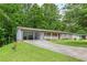 View of the house exterior with a long driveway and carport amid lush greenery at 2585 Whisper Trail, Douglasville, GA 30135