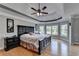 Spacious bedroom with tray ceiling, hardwood floors, large bed, and many large windows overlooking nature at 1943 Blue Heron Way, Lawrenceville, GA 30043