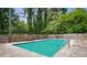 Backyard inground pool with fencing, mature trees, and shrubs at 6134 Silver Spur Dr, Lithonia, GA 30058