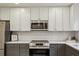 Close-up of kitchen featuring stainless steel appliances, white cabinets and subway tile backsplash at 104 Verlaine Nw Pl, Atlanta, GA 30327