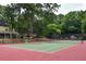 Outdoor tennis court with red and green surface, surrounded by lush trees and black fence at 104 Verlaine Nw Pl, Atlanta, GA 30327