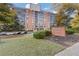 Brick condo building with a beautifully landscaped front yard and sign for Brookwood Park at 130 26Th St # 706, Atlanta, GA 30309