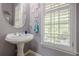 Stylish powder room with a pedestal sink, modern fixtures, and a window with shutters at 4891 Tarry Post Ln, Suwanee, GA 30024